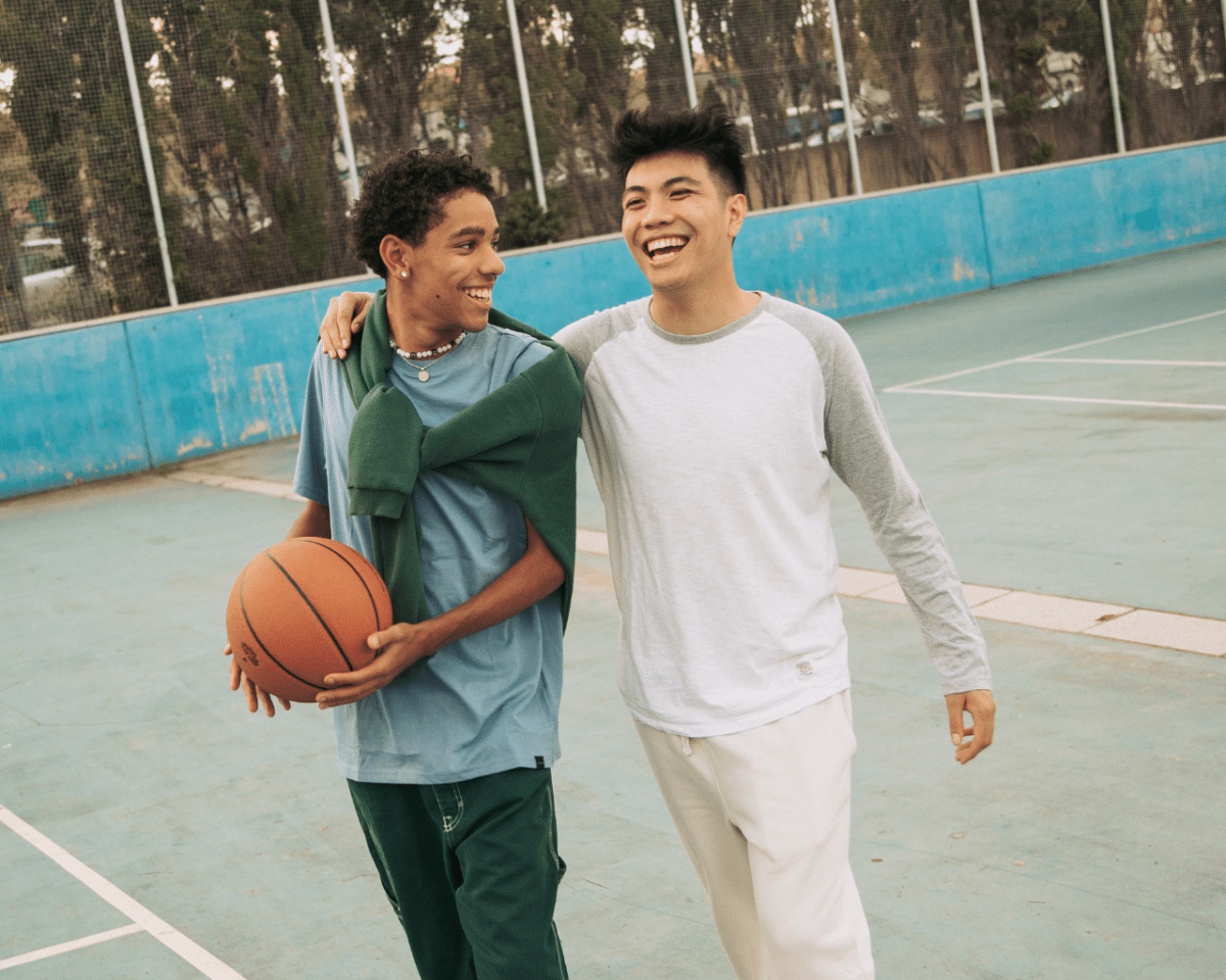 Twee jongens lachen op een basketbalveld